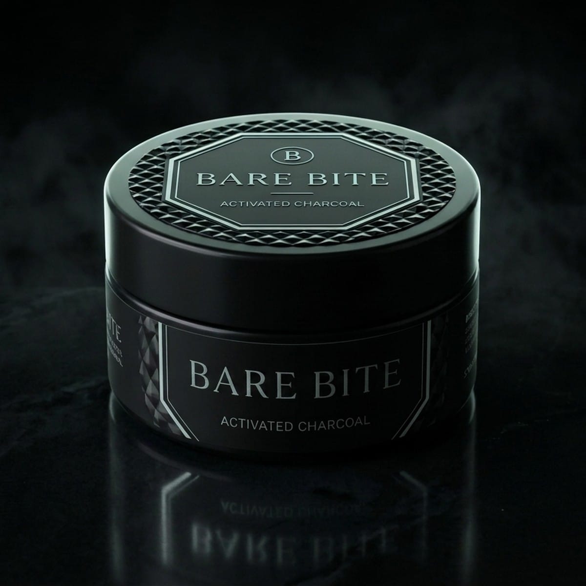 BARE BITE activated charcoal tooth powder, 30 g black jar with faceted lid and octagon label, on dark stone