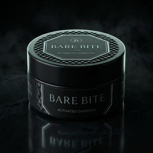 BARE BITE activated charcoal tooth powder, 30 g black jar with faceted lid and octagon label, on dark stone